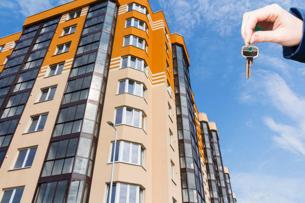 istock Hand with keys in the background apartment building. 1026769284