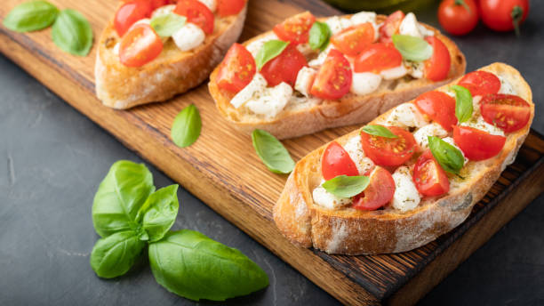 istock Bruschetta with tomatoes, mozzarella cheese and basil on a cutting board. Traditional italian appetizer or snack, antipasto 1026777068