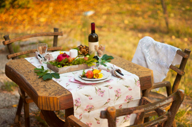 istock Romantic dinner in the autumn garden, table setting for a nice dinner. Wine, fruit, pomegranate and flowers. Picnic in the open air. 1026777334