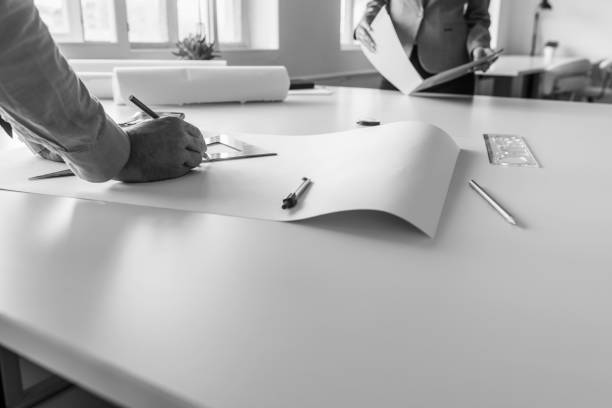 istock Black and white image of architects measuring and drafting plans 1026780048