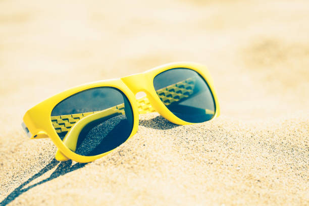 istock Vintage style - sunny yellow glasses on a sandy beach 1026784184