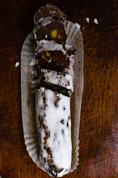 Chocolate salami on wooden background, with nuts