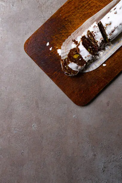 Chocolate salami on wooden background, with nuts