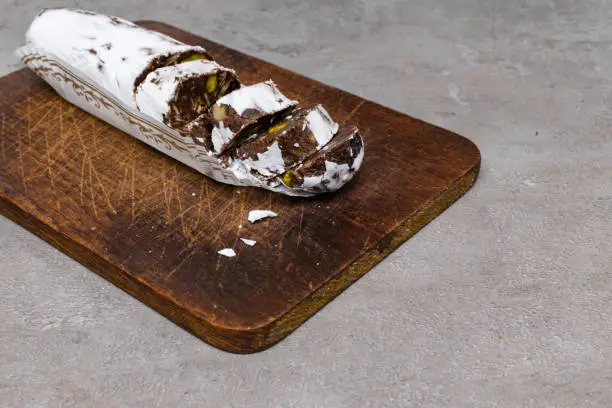 Chocolate salami on wooden background, with nuts