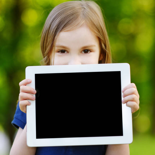 istock Happy child holding tablet PC outdoors 1026796632