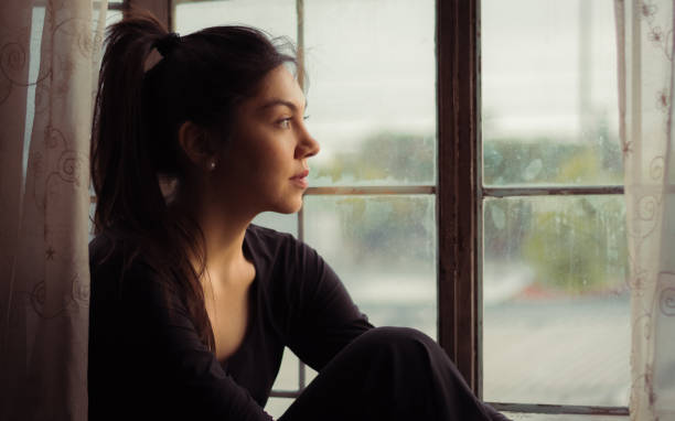 istock Woman watching through the window 1026797008