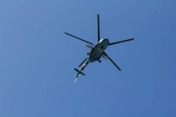 Military helicopter maneuvers in the blue sky.