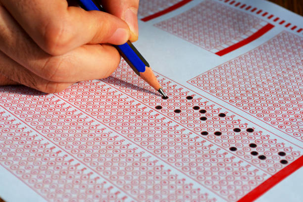 istock Hand with pencil filling out answers on exam test answer sheet 1026799482
