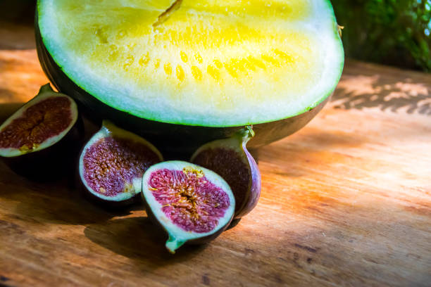 yellow watermelon without bones and red figs on a wooden background exotic fruits