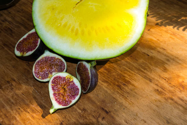 yellow watermelon without bones and red figs on a wooden background exotic fruits