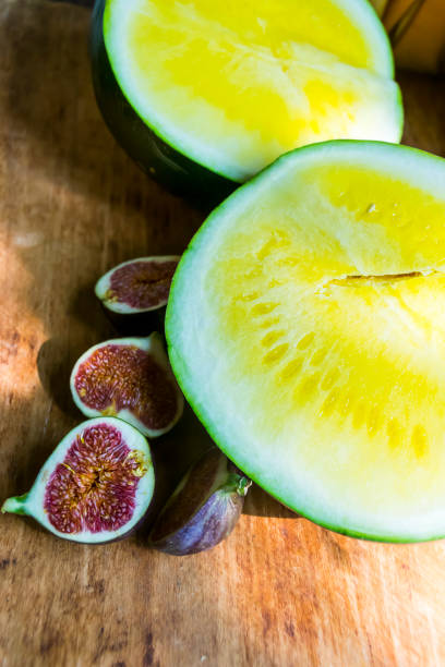 yellow watermelon without bones and red figs on a wooden background exotic fruits