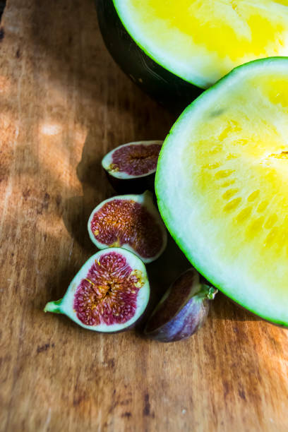 yellow watermelon without bones and red figs on a wooden background exotic fruits