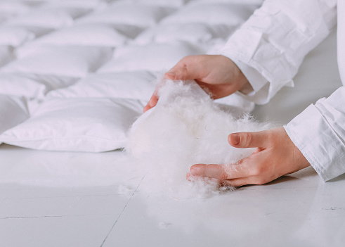 production of down duvets work with feather products light white fluff keeps in hands 
view from sides