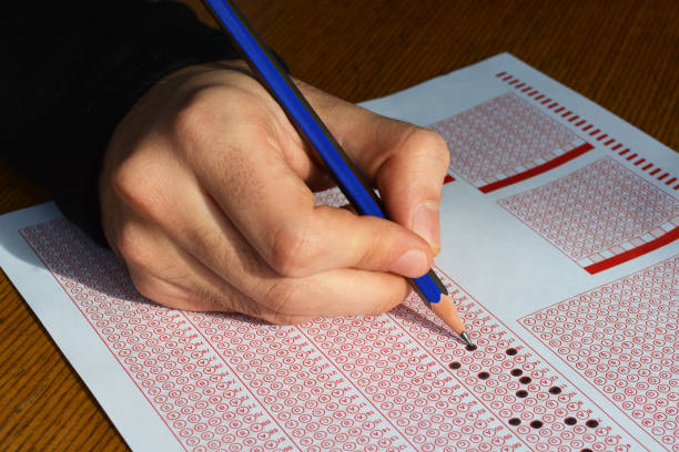 istock Hand with pencil filling out answers on exam test answer sheet 1026811922