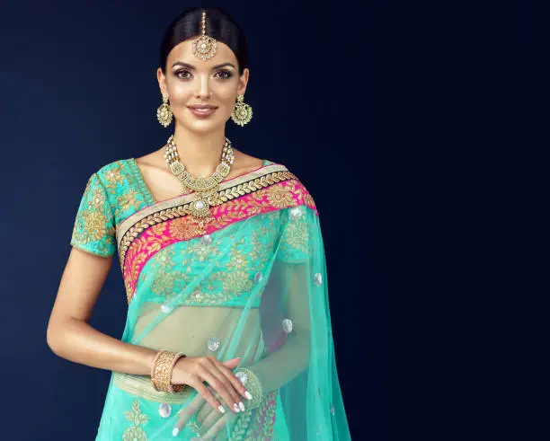 Photo of Portrait of beautiful girl dressed in a traditional indian national suit, jewelry set, blouse and shawl (dupatta).