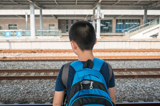 Elementary age Asian boy travel with train with backpack