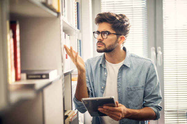 istock Young cute hipster student looking for some important books in library. 1026852106