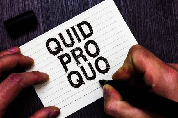 Photo of Text sign showing Quid Pro Quo. Conceptual photo A favor or advantage granted or expected in return of something Man holding marker notebook page communicate ideas Wooden background