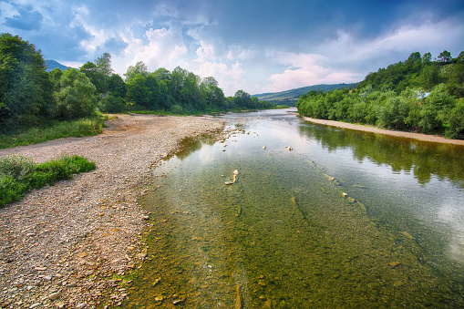 Mountain river stream of water in the rocks with majestic blue sky. Clear river with rocks. Stone foreground. Carpathian region. Ukraine