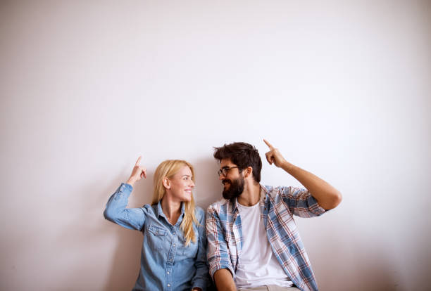 Happy young modern couple standing against the wall. Happy young modern couple standing against the wall. two people thinking stock pictures, royalty-free photos & images