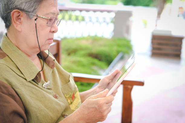 istock elder woman holding tablet. elderly senior female texting message, using app with touchpad outdoor 1026871272