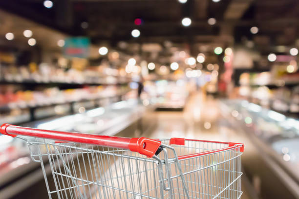 Empty shopping cart with abstract blur supermarket discount store aisle and product shelves interior defocused background Empty shopping cart with abstract blur supermarket discount store aisle and product shelves interior defocused background thailand mall stock pictures, royalty-free photos & images