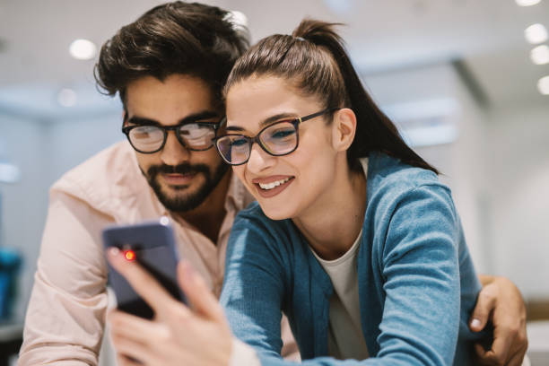 istock Young modern beautiful couple is testing new telephone in tech store. 1026871720