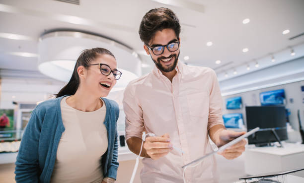istock Charming handsome man enjoy looking through some new tablet with his girlfriend in tech store. 1026872216