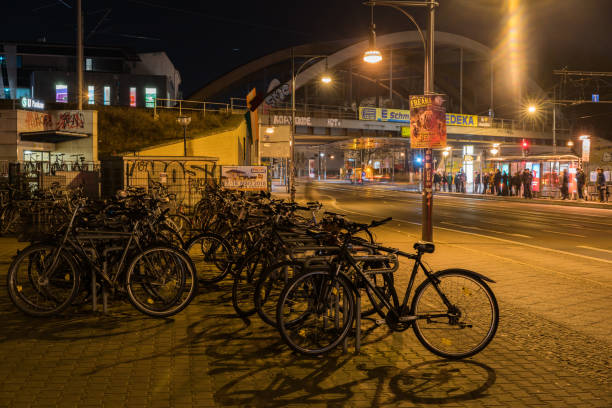 Berlin, Germany, Europe - February 20, 2018: Berlin  view showing parked bicycles on the sideway of the road, bridge and line of people waiting for buses  at night in the Pankow area