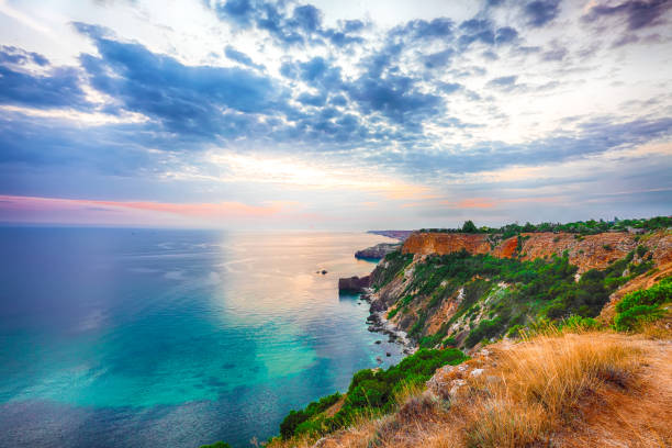 Rocky coast with cliff and green grass. Blue sea