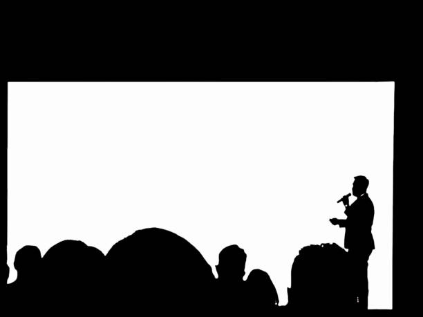 Silhouette businessman giving a speech on stage with blank big screen as the background