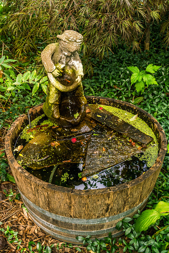 A  vintage wooden novelty garden water fountain and feature in a serene and tranquil setting.