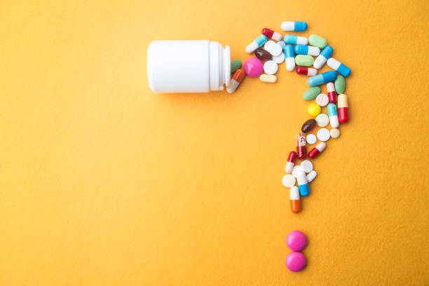 Pills or capsules as a question mark and white plastic bottle. stock photo