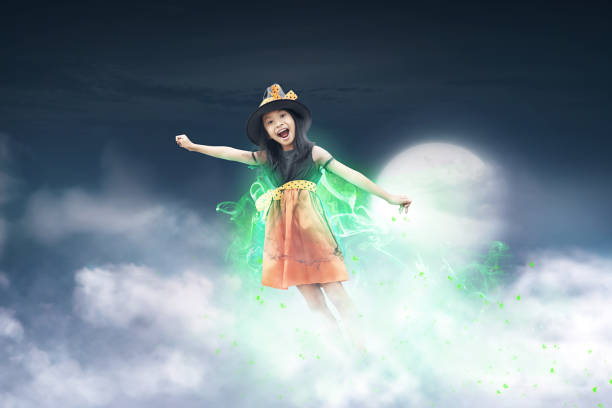 Cheerful asian witch girl flying with her magic power. Halloween concept