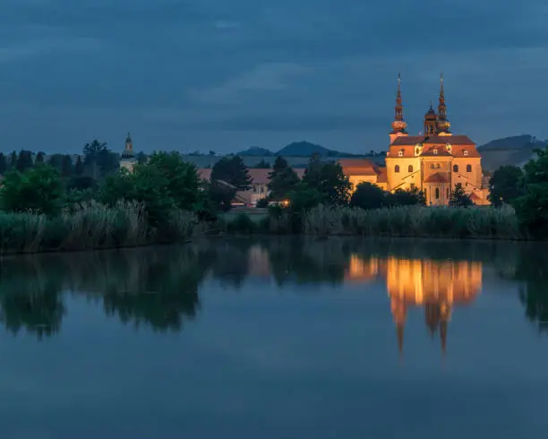 Beautiful pilgrimage church in Velehrad, Czech Republic, photographed during a night photography. Symetrical night photography of a church reflected in a pond.
