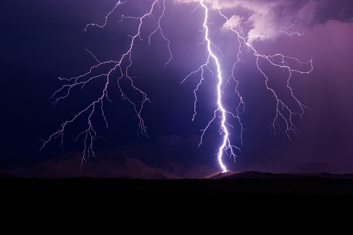 Lightning bolt strikes a mountain in front of the Four Peaks during a storm near Phoenix, Arizona.