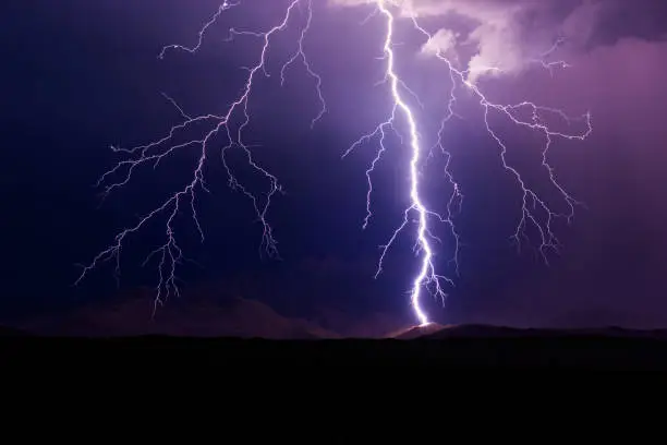 Photo of Lightning bolt strikes a mountain during a storm.
