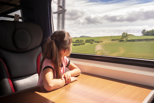 Pretty 8 year old Eurasian (mixed race) girl is enjoying taking the train from Edinburgh to York, and is somewhere in the middle of rural Yorkshire. She's enjoying the view out of her window set.