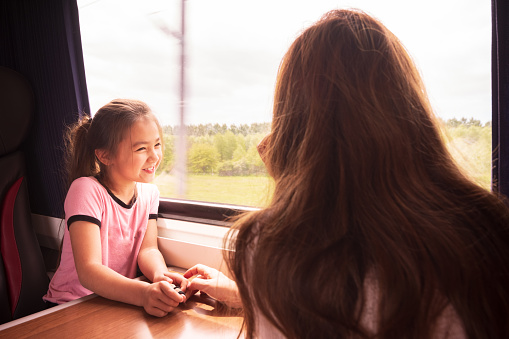 Pretty 8 year old Eurasian (mixed race) girl is enjoying taking the train from Edinburgh to York, and is somewhere in the middle of rural Yorkshire. She's enjoying the view out of her window set. She's traveling with her mother.