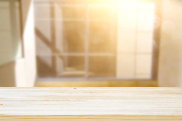 istock image of wooden table in front of abstract blurred window light background. 1026960802