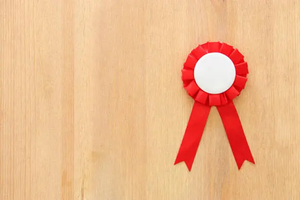 Photo of red award ribbon over wooden table