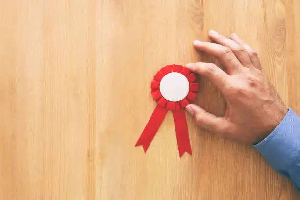 Photo of red award ribbon over wooden table