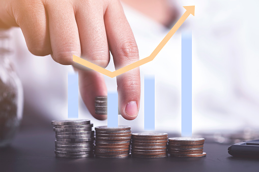 Saving money and investment concept. Female hand stack coins to shown concept of growing business and wealthy. added graphs