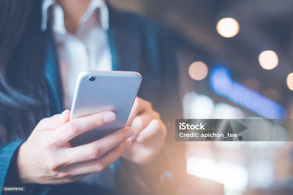 Mão de mulheres de negócios estão usando telefones celulares no escritório. - Foto de stock de Telefone celular royalty-free