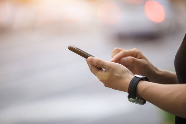 istock Woman hands using smartphone at city street side 1026989272