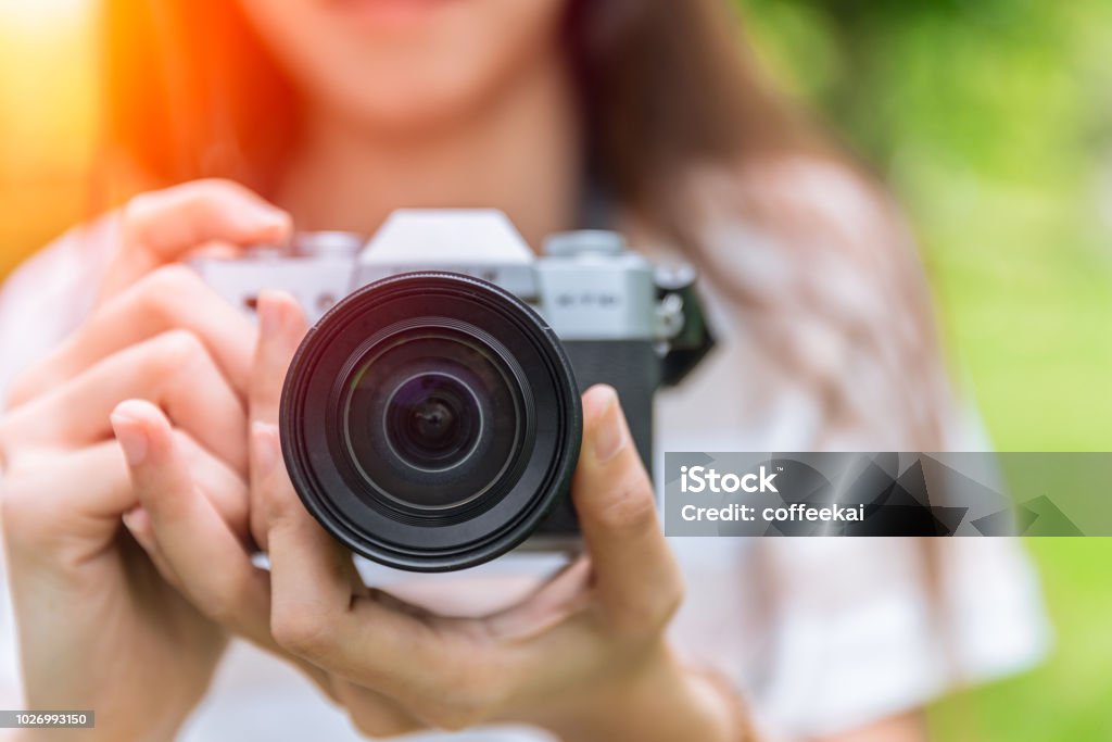 closeup front lens of mirrorless camera in woman teen photographer Camera - Photographic Equipment Stock Photo