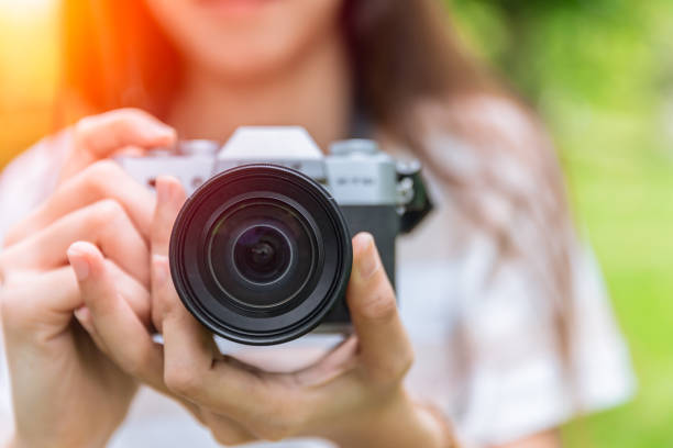 крупным планом передний объектив безмысненной камеры в женщине подросток фотограф - студент фотографии стоковые фото и изображения