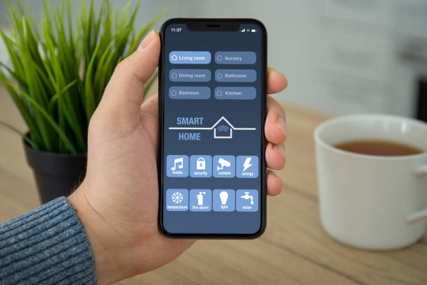 istock Male hand holding black touch phone with app smart home 1026995654