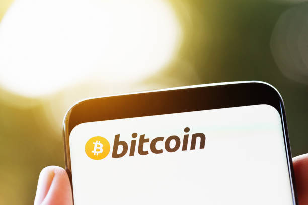 istock Hand holds smart phone with Bitcoin name and logo 1027005294