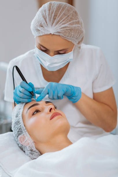 istock Serious skilled female dermatologist removing a mole 1027005360